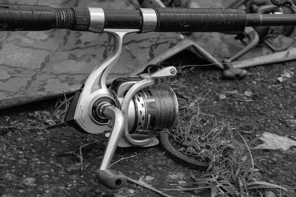 Carrete de spinning montado en una caña junto a un lago