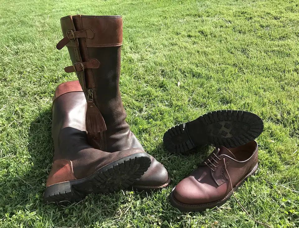 Botas altas de piel y zapatos de campo con suela de montaña sobre la hierba